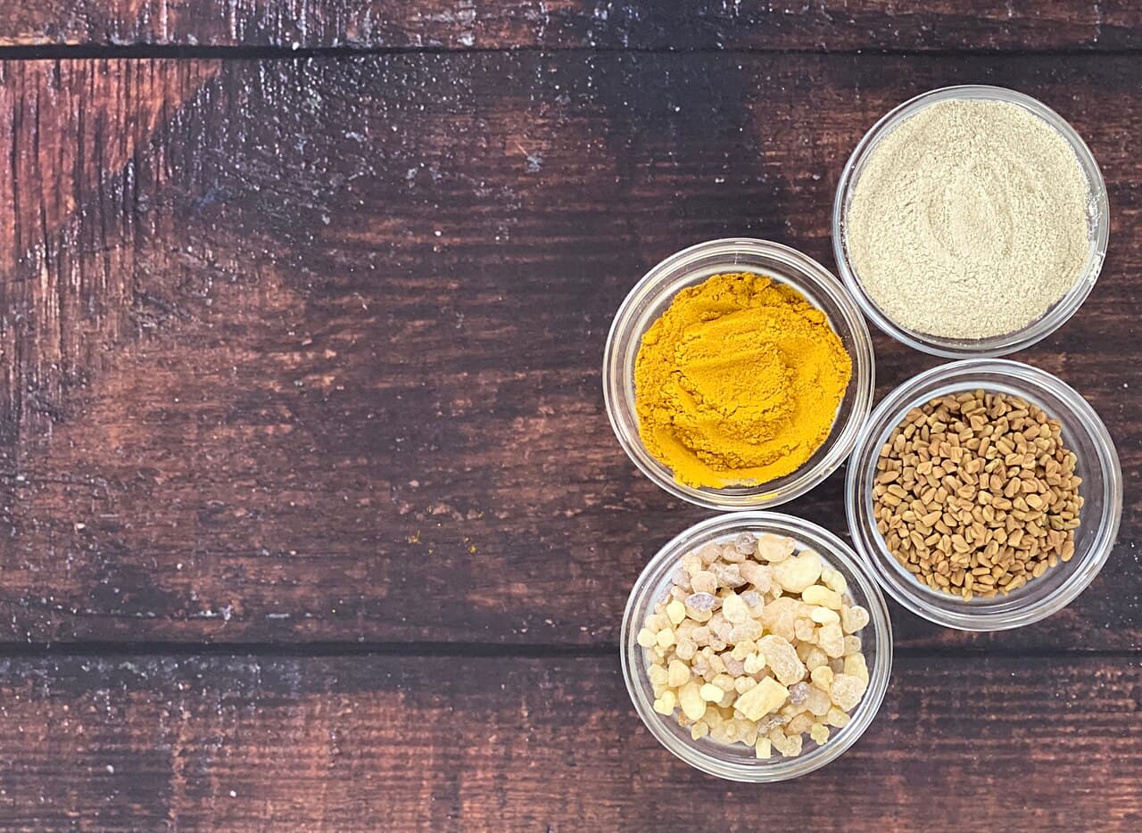 Turmeric, fenugreek, ashwagandha and boswellia on wooden spoons — classic Ayurvedic herbs